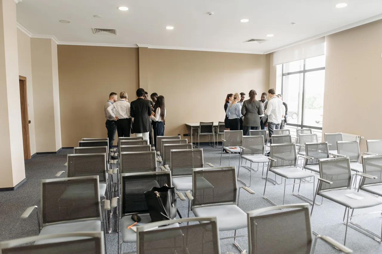 Small groups talking in a bright conference room; illustrative stock photograph